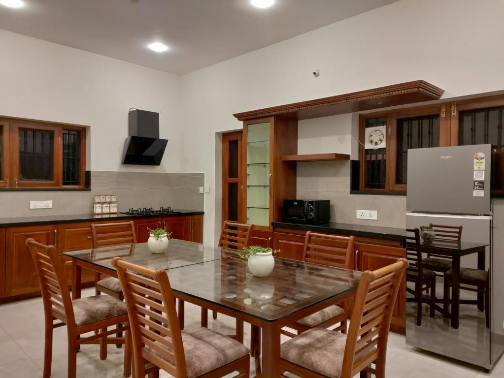 a kitchen with a table and chairs and a refrigerator at The Cana's Coorg in Ammatti