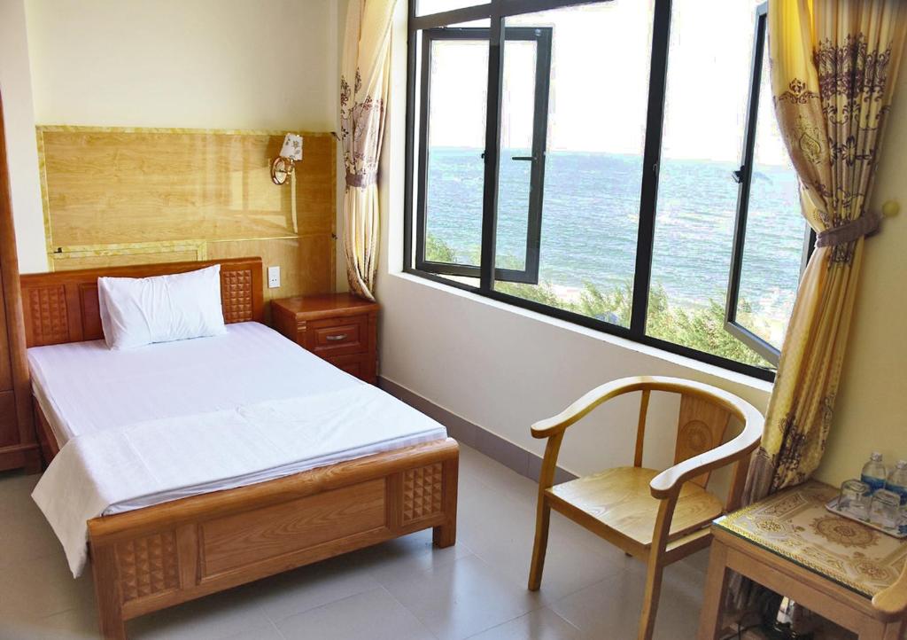 a bedroom with a bed and a chair and a window at Thăng Long Hotel in Dong Hoi