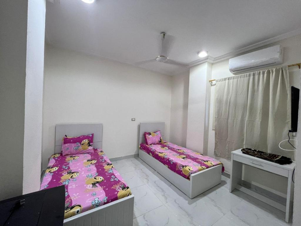 a bedroom with two beds and a tv in it at Moon light Hotel in Kafr Mas‘ūd