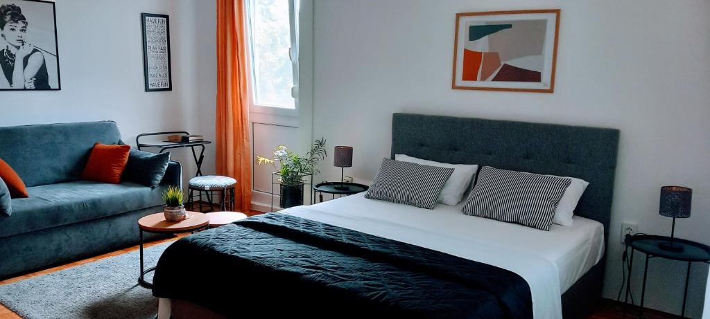 een slaapkamer met een bed en een bank bij Apartman studio MINNA Osijek, free parking in Osijek