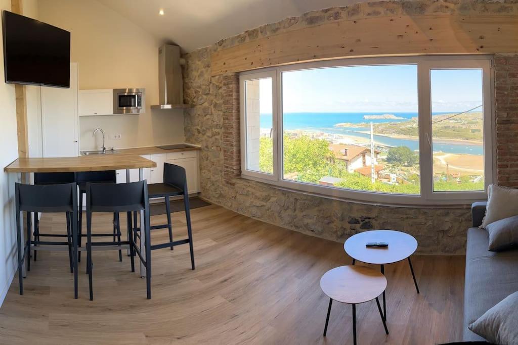 a kitchen and living room with a large window at Apartamentos playa Buendia in Suances