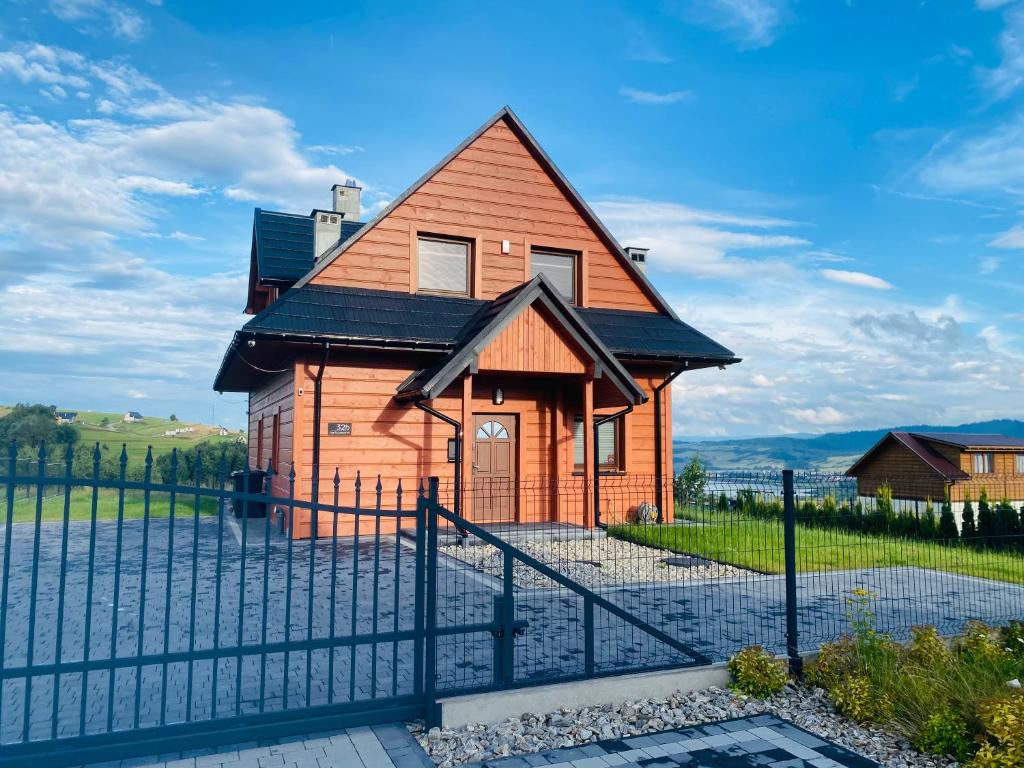 uma casa com uma cerca em frente em Scenic Chalet Malowniczy Domek em Szlembark