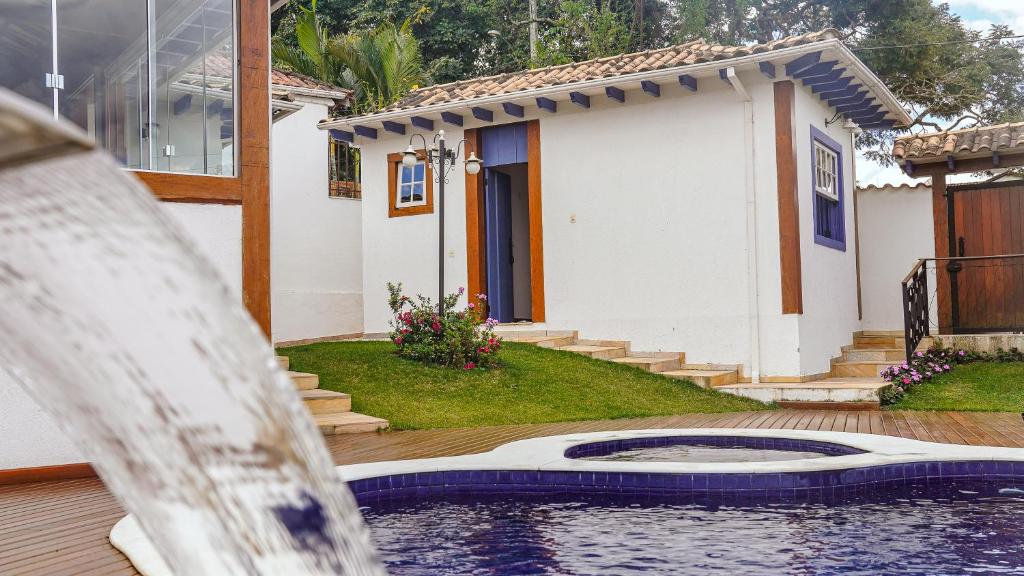 a house with a swimming pool in front of a house at Flat com Piscina no Centro de Tiradentes in Tiradentes