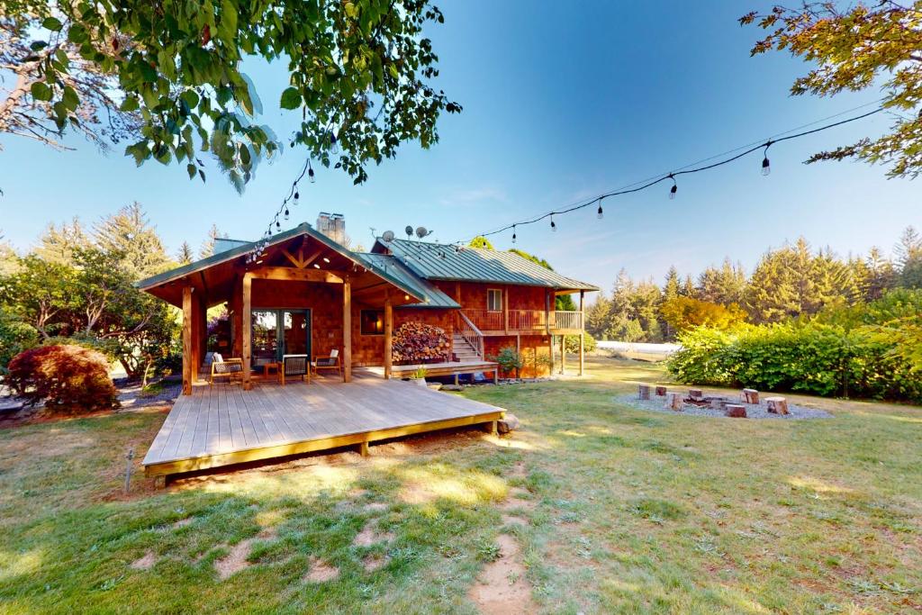 a log cabin with a large deck in the yard at Emerald Acres in McKinleyville