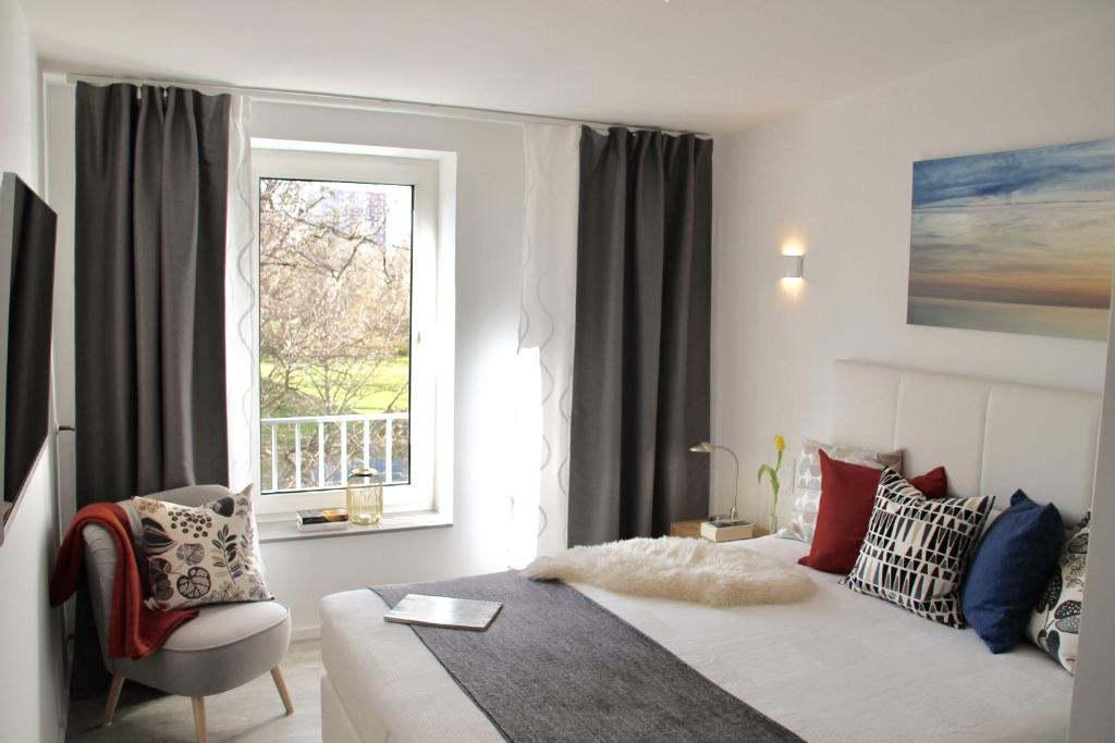 1 dormitorio con cama, ventana y silla en Living Concept Bogenhausen, en Múnich