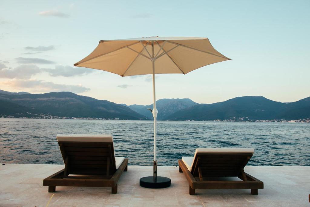 two chairs and an umbrella in front of the water at Casa Brilla in Tivat