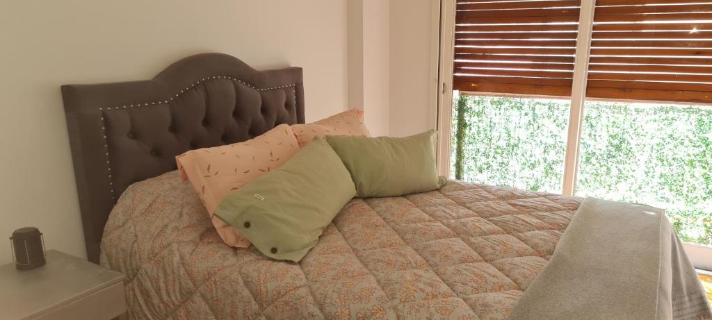 1 dormitorio con cama con almohadas y ventana en Dpto. Recoleta en Buenos Aires