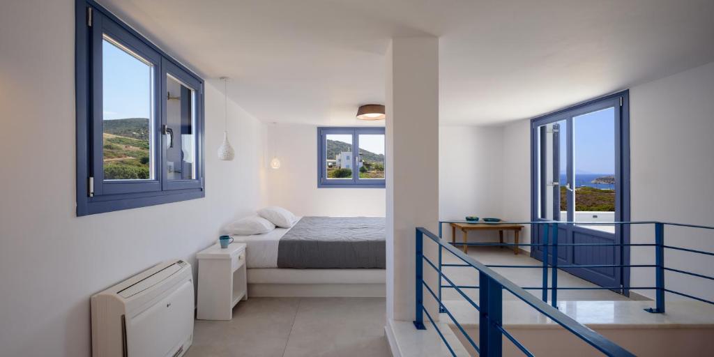 a white bedroom with a bed and two windows at White Dream Suites Antiparos in Andiparos