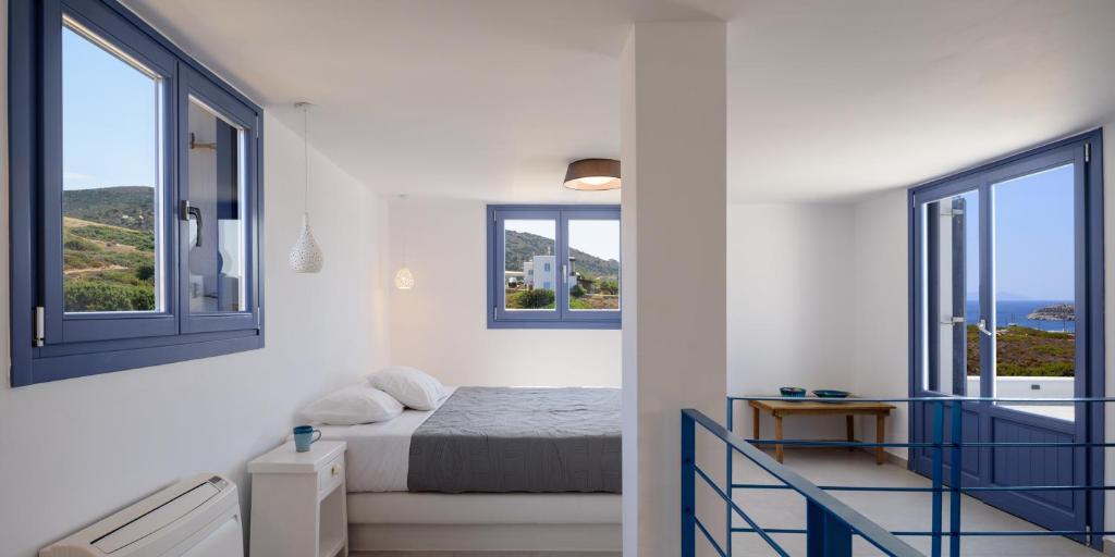 a white room with a bed and two windows at White Dream Suites Antiparos in Antiparos