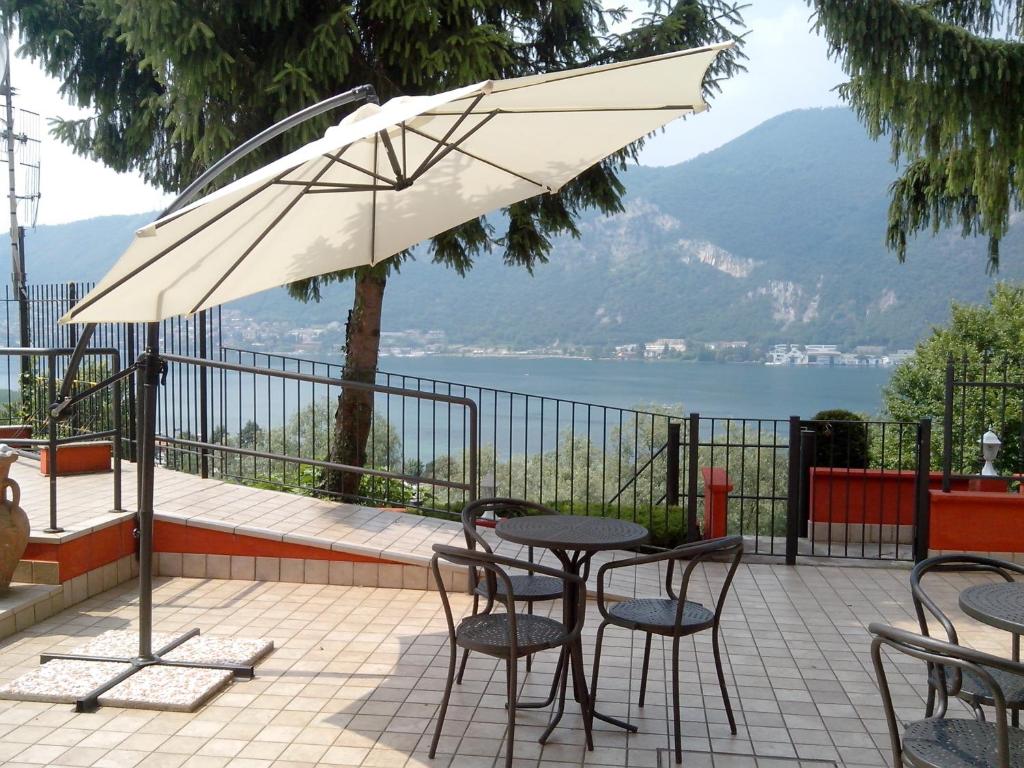 een patio met een tafel en stoelen en een parasol bij Hotel Empire Resort in Iseo