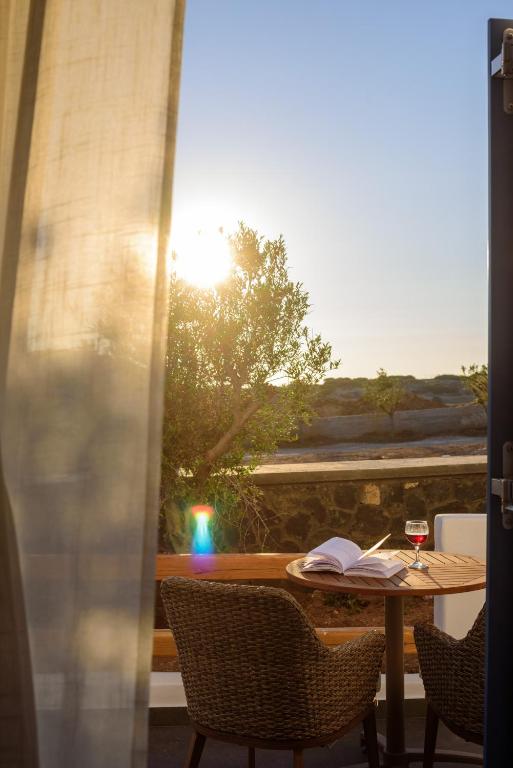 a table with a book and a glass of wine at White Dream Suites Antiparos in Antiparos