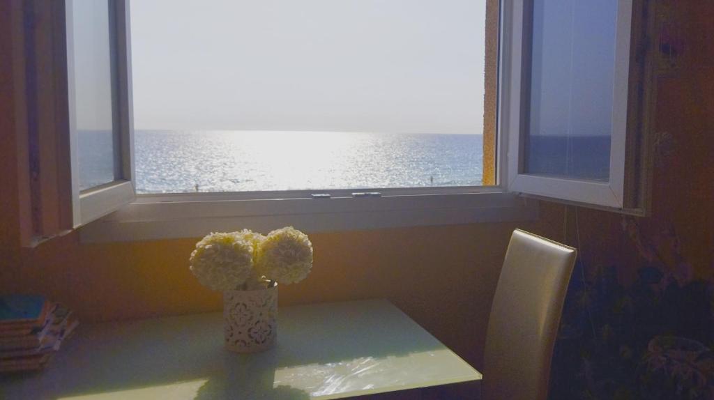 un jarrón de flores sentado en una mesa frente a una ventana en Primera línea, magníficas vistas al mar y a la playa, en Retamar