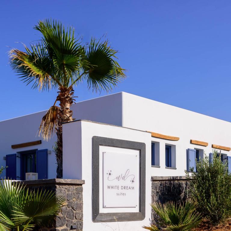 a sign in front of a white house with a palm tree at White Dream Suites Antiparos in Antiparos