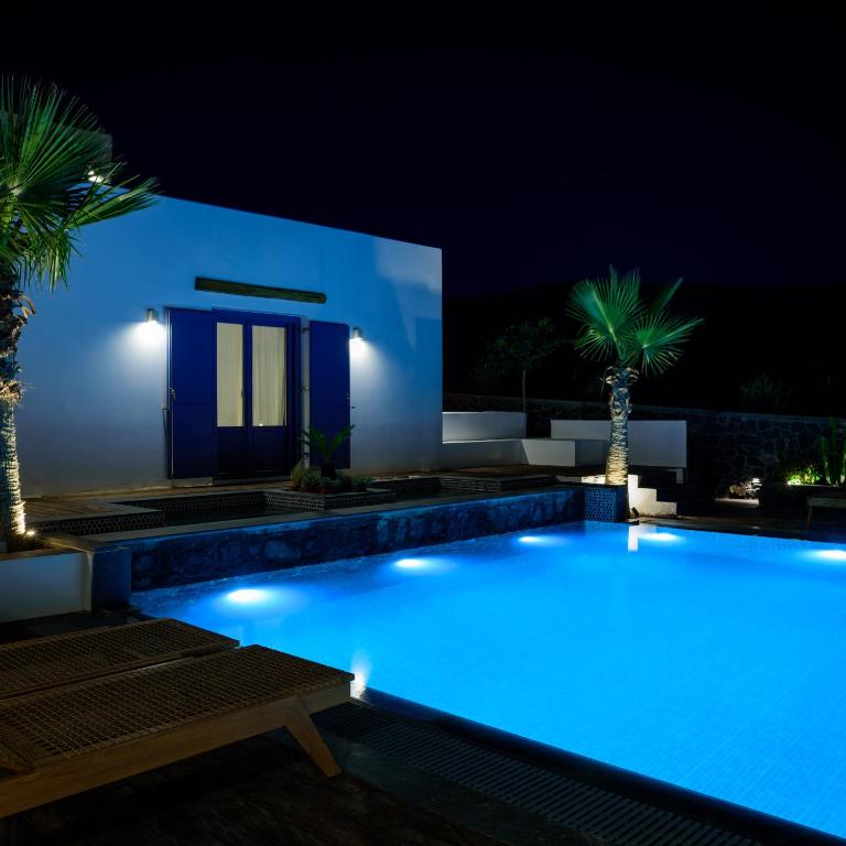a swimming pool lit up at night with palm trees at White Dream Suites Antiparos in Antiparos
