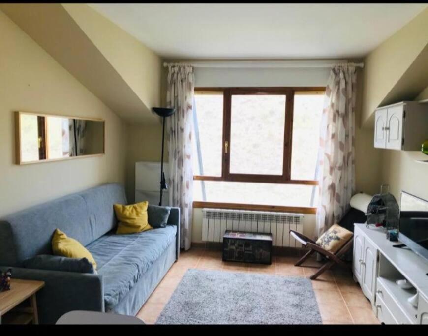 sala de estar con sofá azul y ventana en Apartamento con encanto, en Jaca