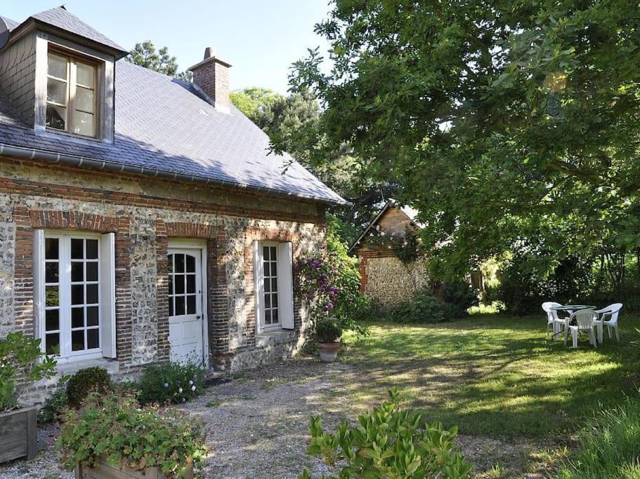 une maison en briques avec une table et des chaises dans la cour dans l'établissement clos du Mont maison sur falaise, à Étretat
