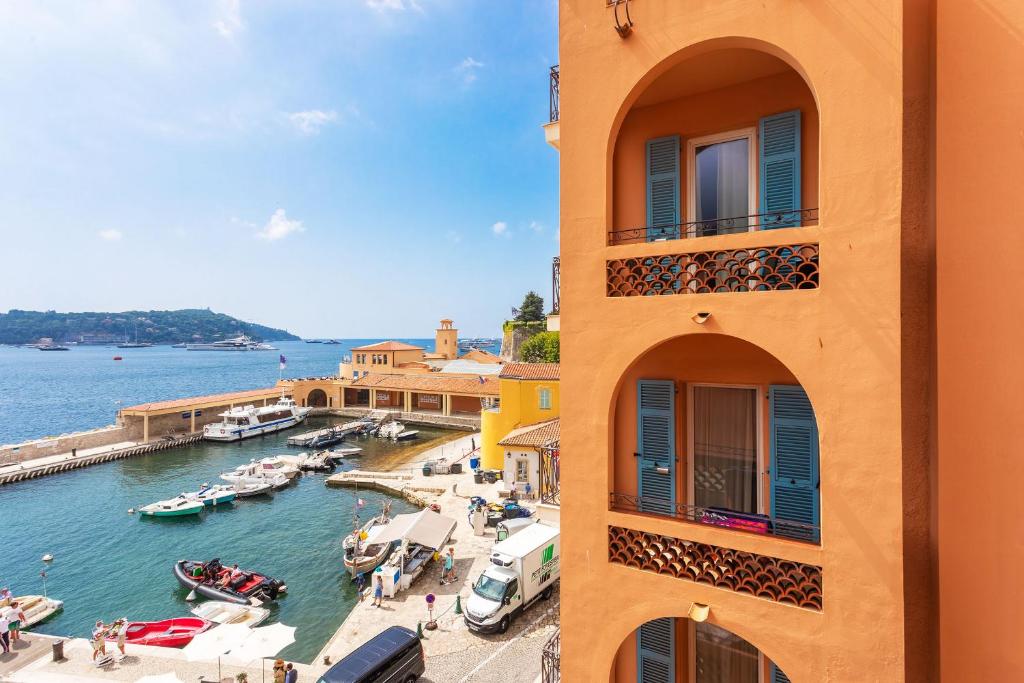 un bâtiment à côté d'un port de plaisance avec des bateaux dans l'eau dans l'établissement THE BAY AP4371 By Riviera Holiday Homes, à Villefranche-sur-Mer