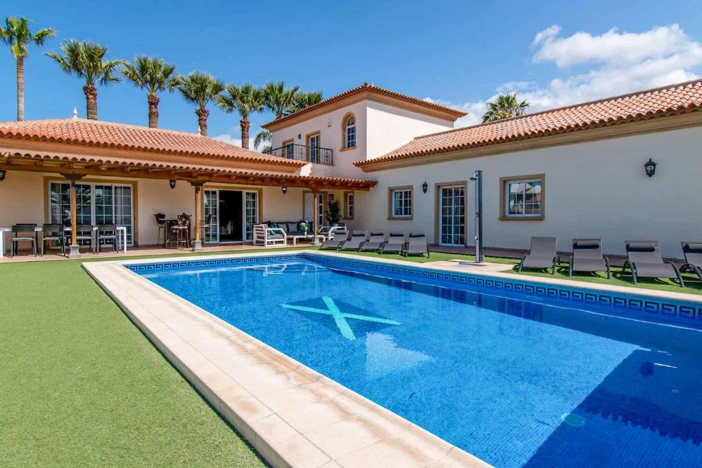 een zwembad voor een huis met palmbomen bij Villa Guapa in San Miguel de Abona