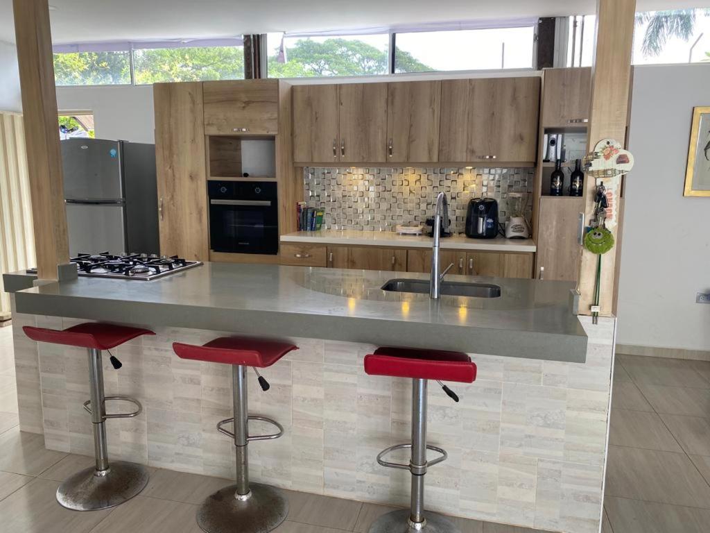 a kitchen with a large counter with red bar stools at Hermosa Casa Campestre in Cúcuta