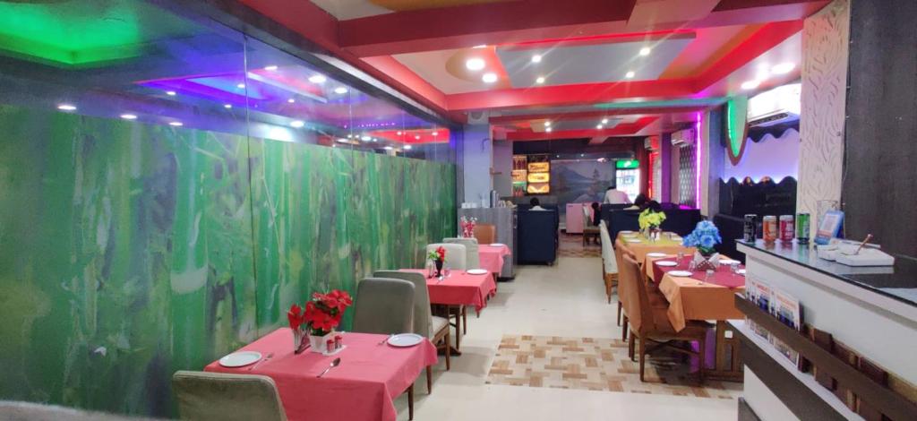 een restaurant met roze tafels en groene muren bij Hotel Nirmala Inn in Jamūi