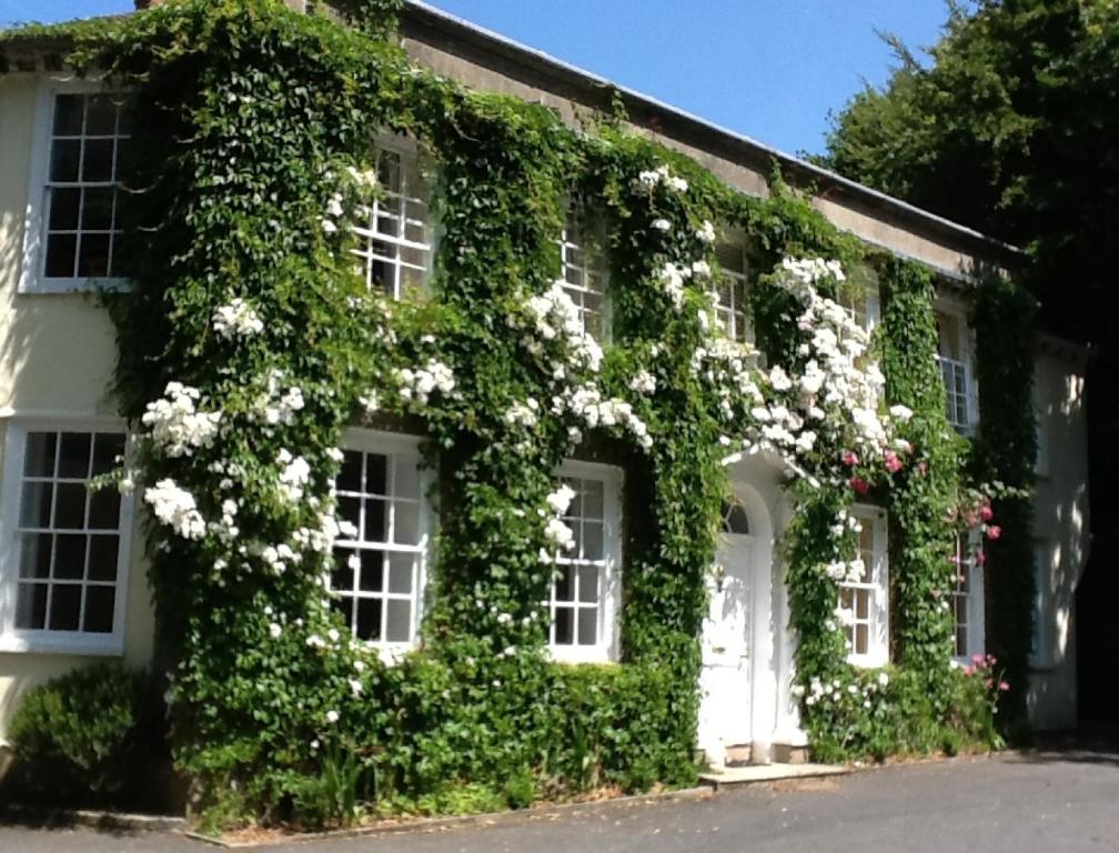 an ivy covered house with white windows and white doors at Rose in Vale Country House Hotel in St. Agnes 