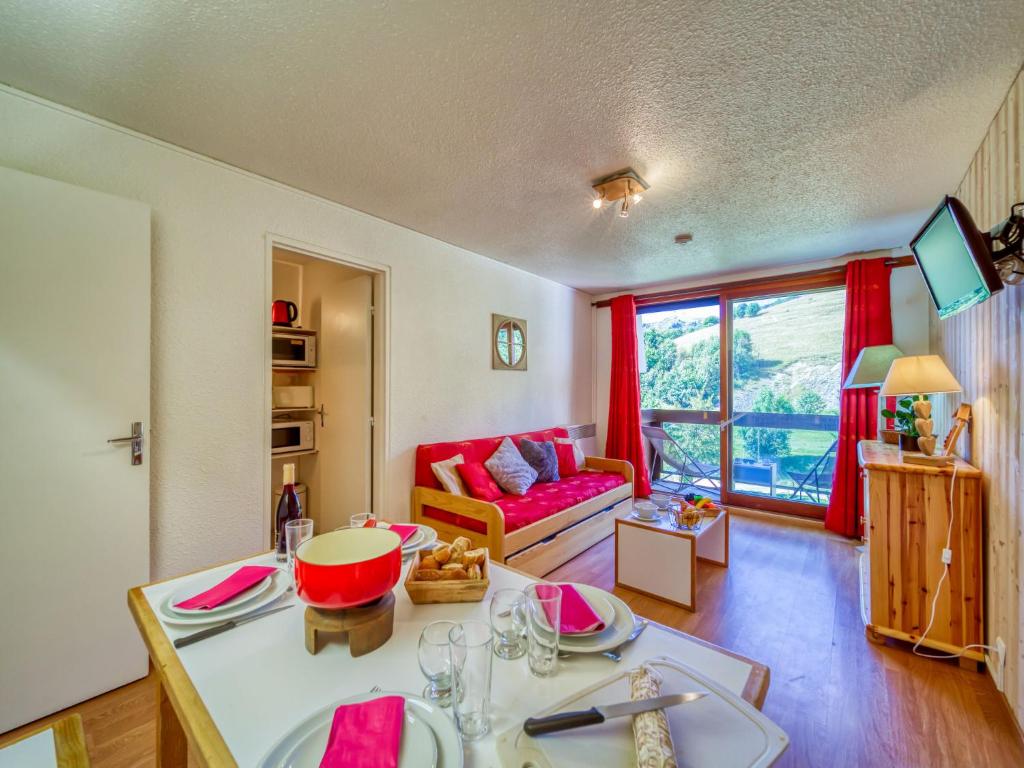 a living room with a table and a red couch at Apartment Pegase Phenix-6 in Le Corbier