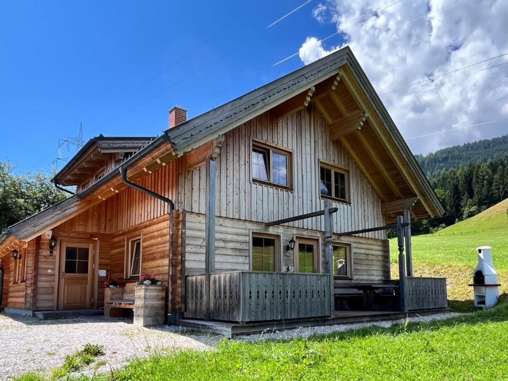 ein Blockhaus mit einer Veranda und einer Liegewiese in der Unterkunft Chalet Grimmingblickhütte - GBM301 by Interhome in Unterlengdorf