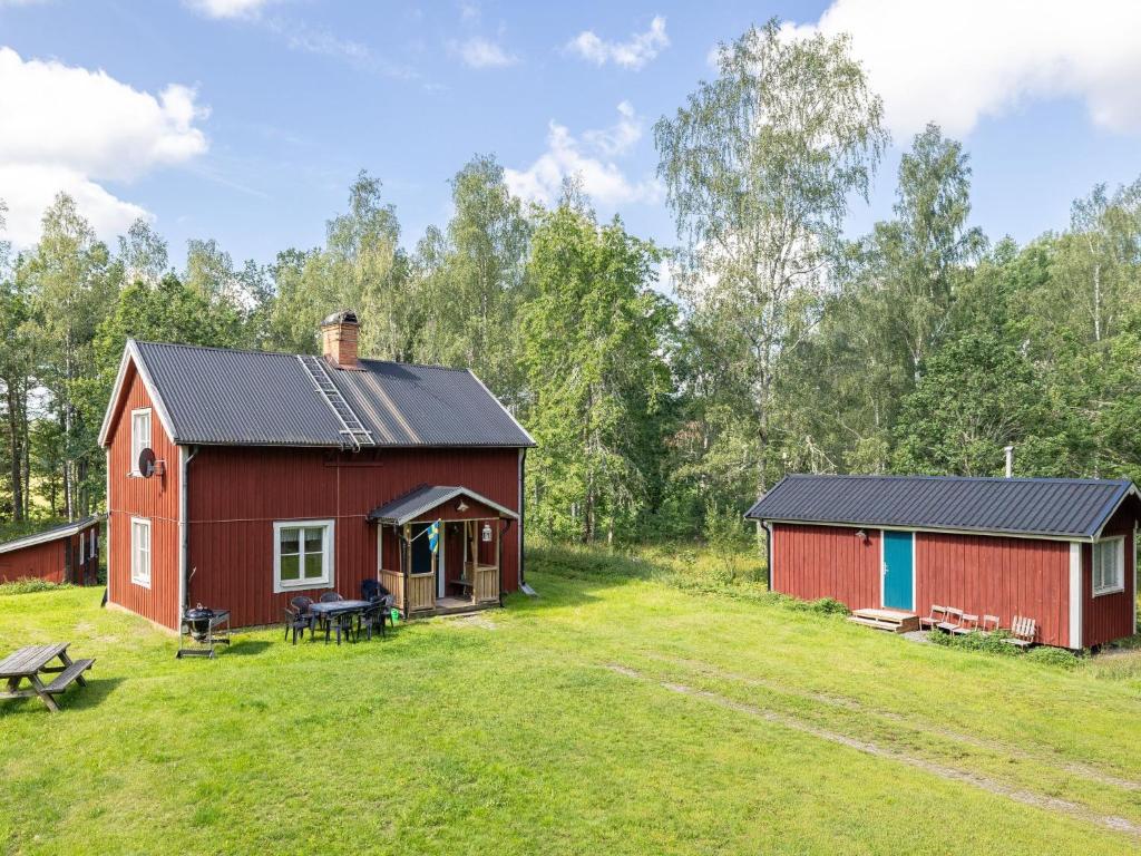 a red barn with a picnic table in a yard at Chalet Mjöshult by Interhome in Hjorted