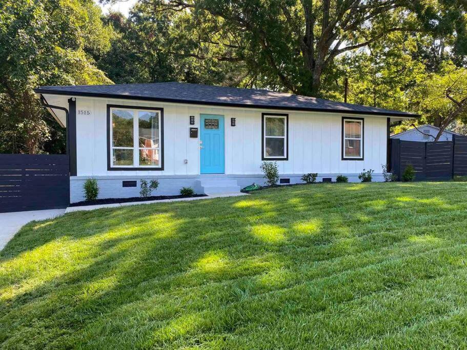 una pequeña casa blanca con una puerta azul en un patio en Modern Home Near Uptown CLT, Airport and More en Charlotte