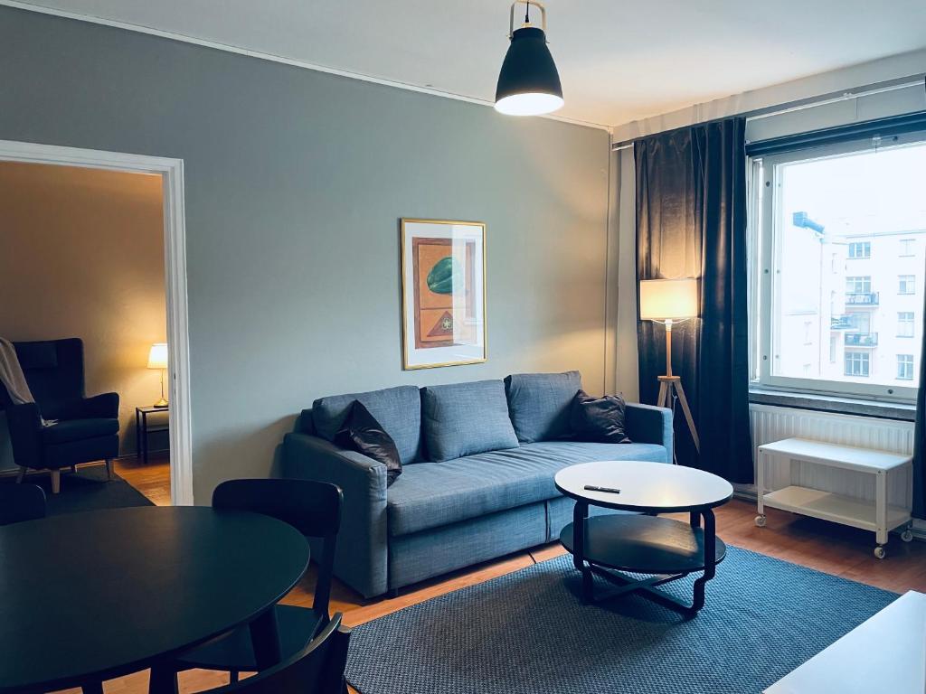 uma sala de estar com um sofá azul e uma mesa em STAY Kamppi Apartment em Helsinque