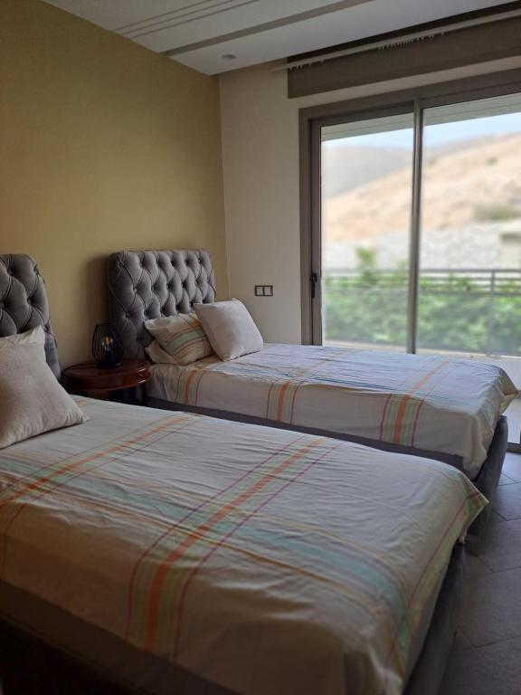 two beds in a room with a window at Couzi Haus Marina in Agadir