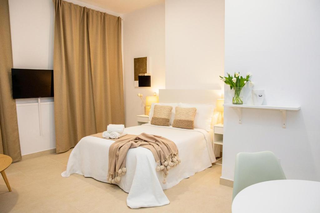 a white bedroom with a bed and a table at Apartamentos La Tahona in Cádiz