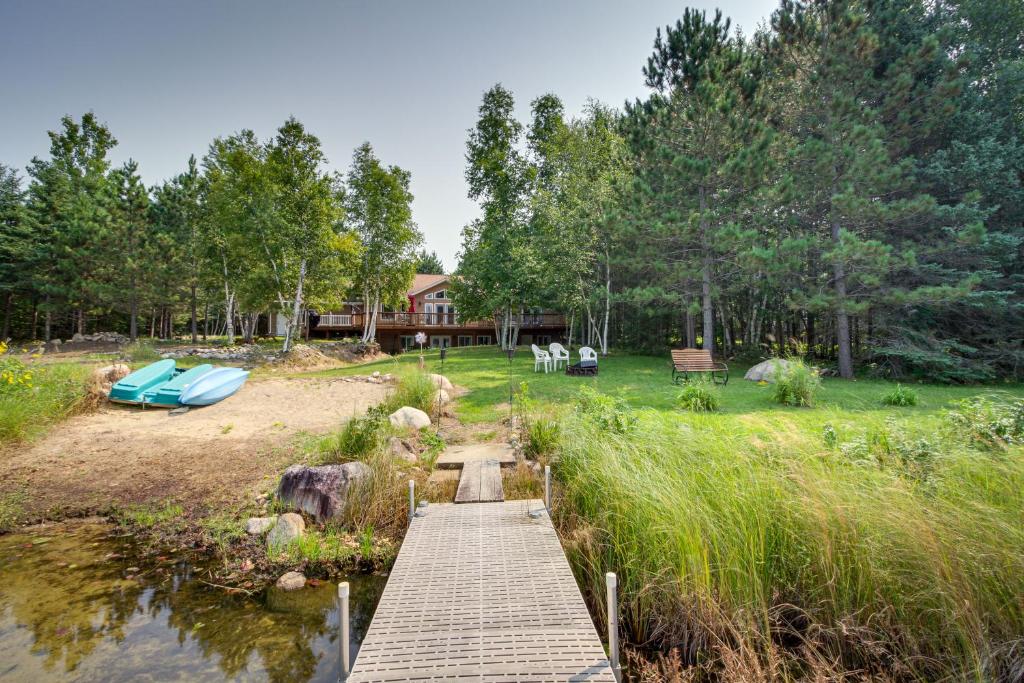 a wooden bridge over a body of water with a house at White Swan Lake Home with Decks and Private Beach! in Bigfork