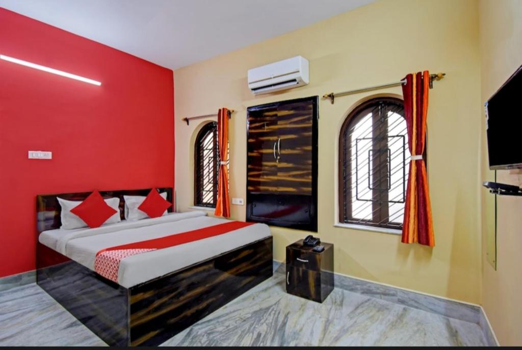 Schlafzimmer mit einem Bett mit roten Wänden und einem TV in der Unterkunft Fantasy Stay Fusion in Kalkutta
