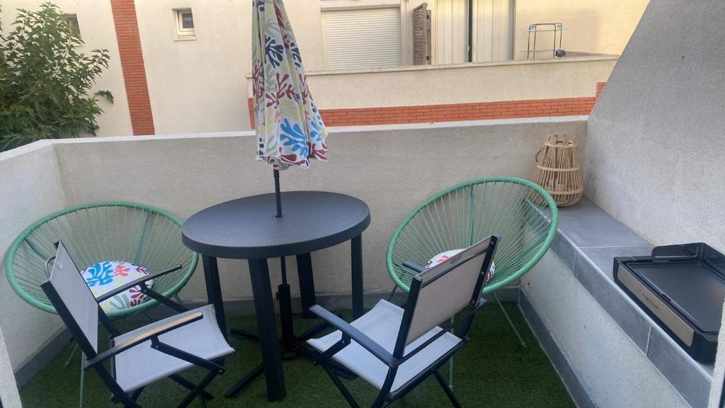 d'une table, de deux chaises et d'un parasol sur le balcon. dans l'établissement Résidence Tahiti Beach Appart bord de mer, piscine à frontignan plage, à Frontignan