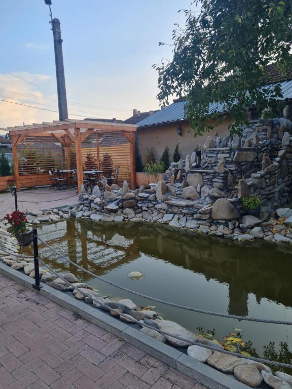 a pond in a yard with a wooden pergola at Secret Garden Sweet Home in Brad