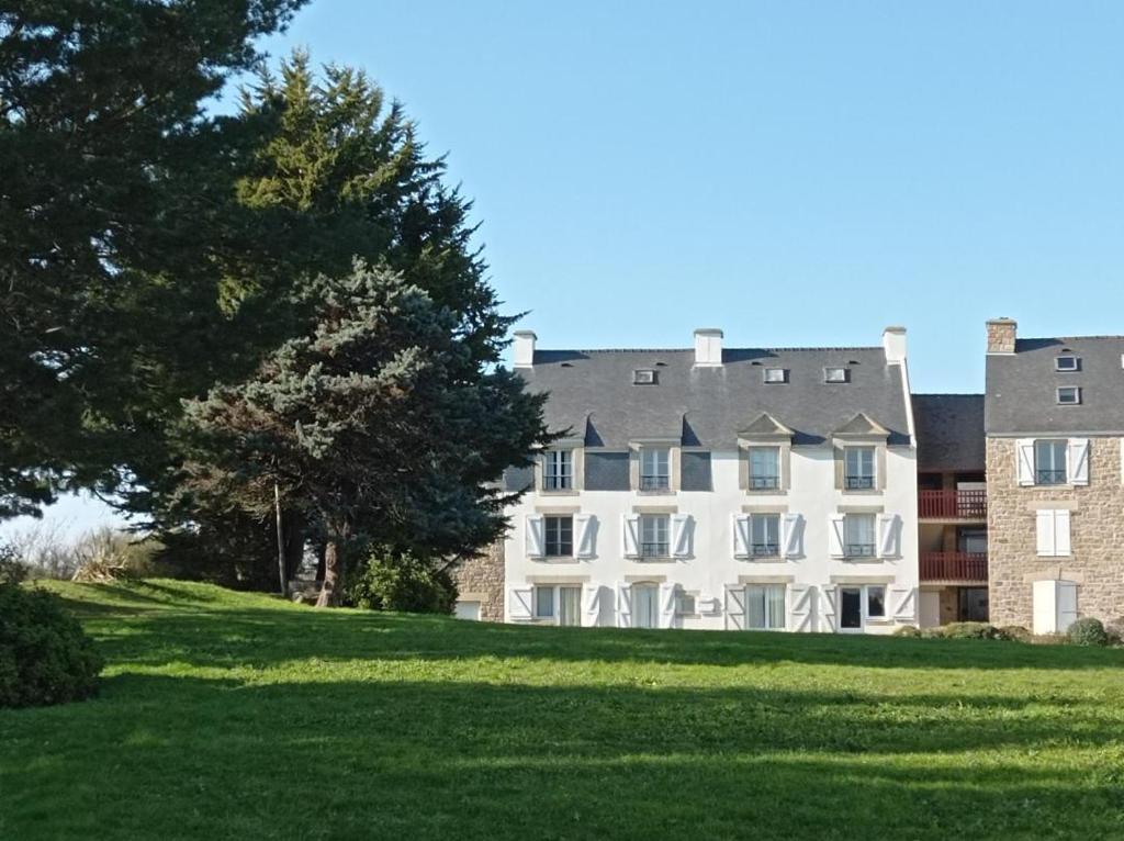 un gran edificio blanco en un césped verde en L'Aigue-Marine emplacement parfait, parking privé, en Arzon