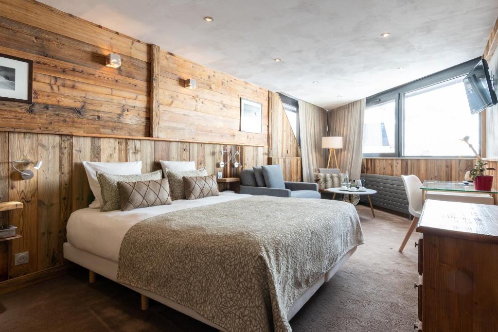 sypialnia z dużym łóżkiem i drewnianymi ścianami w obiekcie Hotel 3 Vallées Val Thorens w Val Thorens