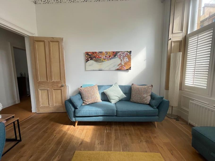 ein Wohnzimmer mit einem blauen Sofa und einem Gemälde in der Unterkunft Stunning West End Flat! in Glasgow