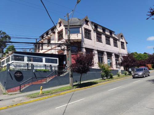 un autobús está estacionado frente a un edificio en una calle en Hostal Florencia, en Puerto Varas