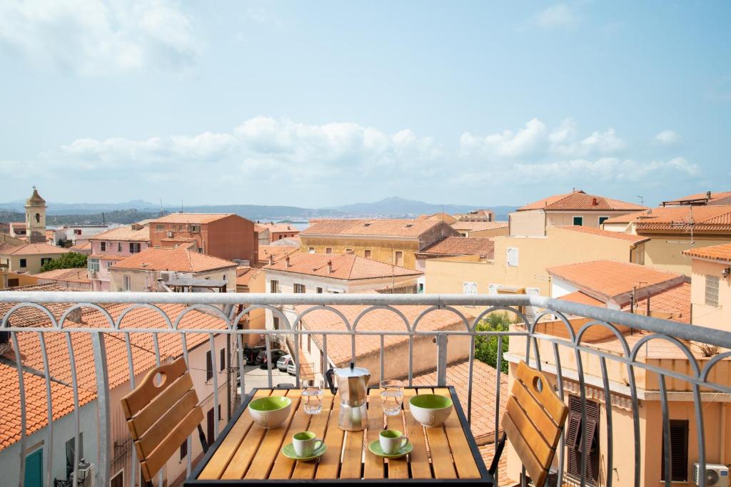 a table on a balcony with a view of a city at Old Charm - Seaview Apartment in La Maddalena