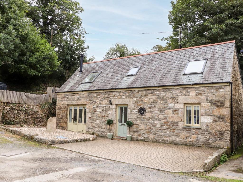 an old stone house with a driveway in front of it at Potters Barn in Helston