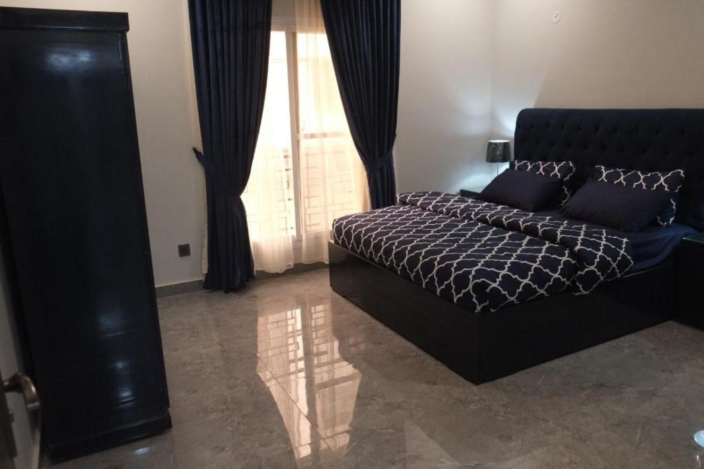 a bedroom with a black bed and a large window at luxurious Family Apartment in Karachi