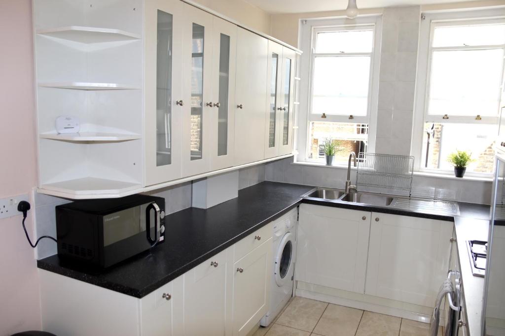 eine weiße Küche mit einer Spüle und einer Mikrowelle in der Unterkunft Baywater - Central London in London