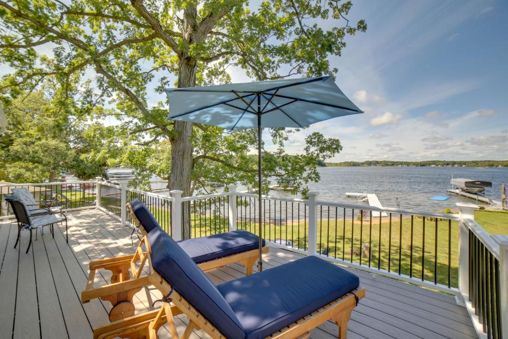 a deck with a chair and an umbrella at Cozy Pierson Paradise Lake Retreat with Fire Pit! in Howard City