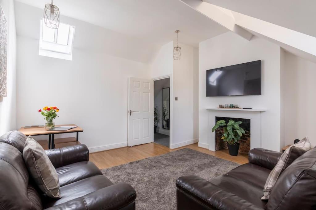 a living room with a leather couch and a fireplace at Castle Garden View in Rochester