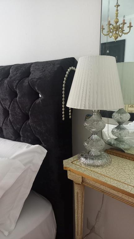 una lampada su un tavolo accanto a un letto di PALAZZO NOVECENTO Rooms a Lecco