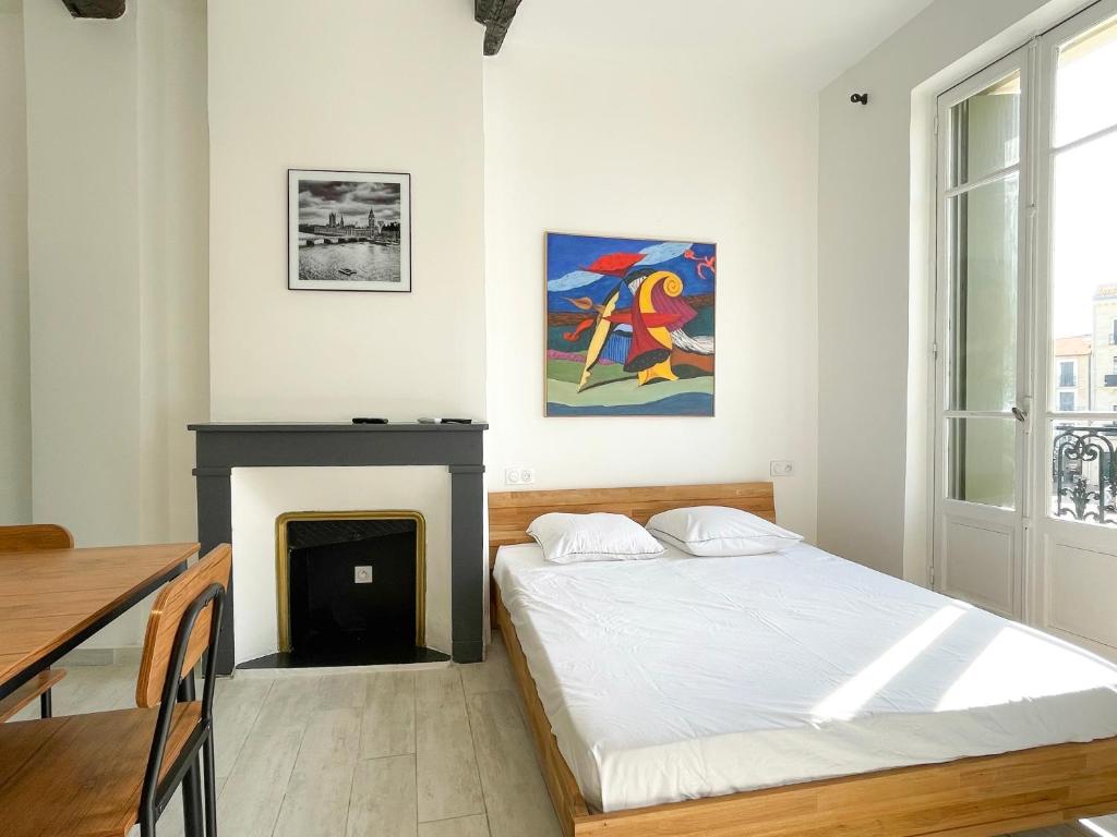 een slaapkamer met een bed en een open haard bij Vue sur la place des Halles, Art Apparts in Béziers