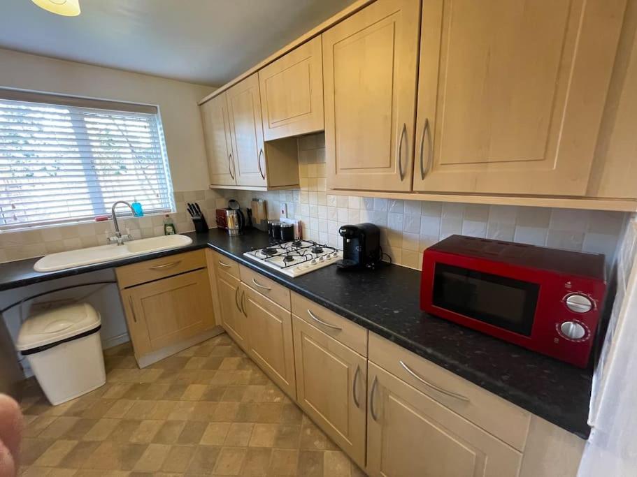 une cuisine avec un four micro-ondes rouge sur un comptoir dans l'établissement 5 Holborn Spacious Home, à Redhill