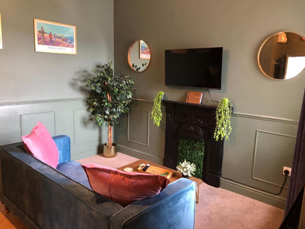 a living room with a couch and a television at Ffau Bach - Little Den in Pembroke Dock